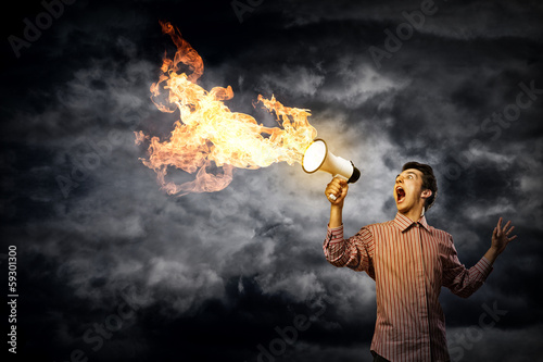 Photo: Portrait of a young man shouting using megaphone Portrait of a young man shouting using megaphone