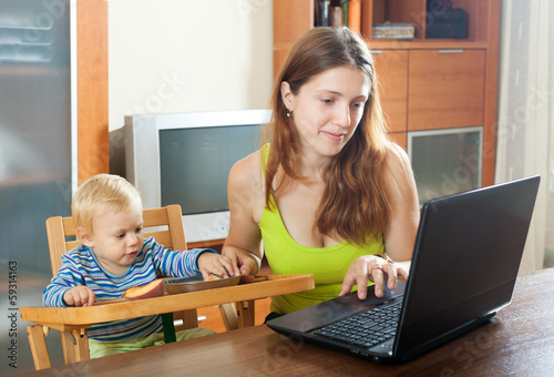 Photo: Woman working with laptop and baby Woman working with laptop and baby