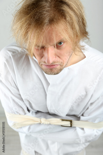 Photo: Mentally ill man in strait-jacket on gray background Mentally ill man in strait-jacket on gray background