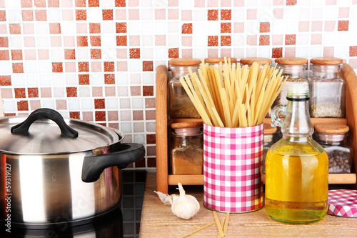 Photo: Pot on stove in kitchen on table on mosaic tiles background Pot on stove in kitchen on table on mosaic tiles background
