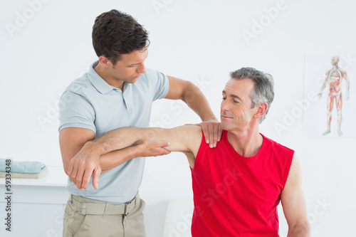 Photo: Physiotherapist massaging mature mans arm Physiotherapist massaging mature mans arm