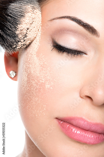 Photo: woman applying dry cosmetic tonal foundation on the face woman applying dry cosmetic tonal foundation on the face