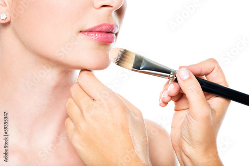 Photo: Makeup artist applying liquid tonal foundation on the face Makeup artist applying liquid tonal foundation on the face