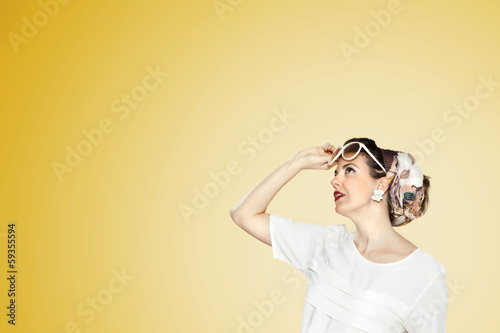 Photo: Woman with glasses looking foward yellow background. Woman with glasses looking foward yellow background.