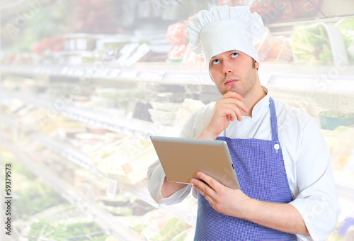 Photo: Handsome chef cook using tablet pc. Place for text. Handsome chef cook using tablet pc. Place for text.