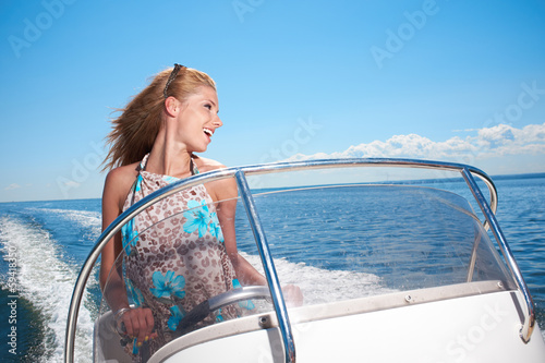 Photo: Summer vacation - young girl driving a motor boat Summer vacation - young girl driving a motor boat