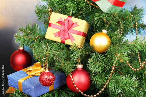 Photo: Gifts on Christmas tree on room background Gifts on Christmas tree on room background