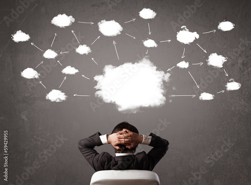 Photo: Businessman sitting with cloud technology above his head Businessman sitting with cloud technology above his head