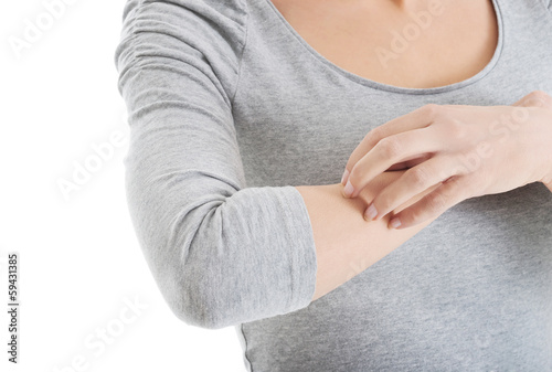 Photo: Young woman is scratching herself on arm. Young woman is scratching herself on arm.