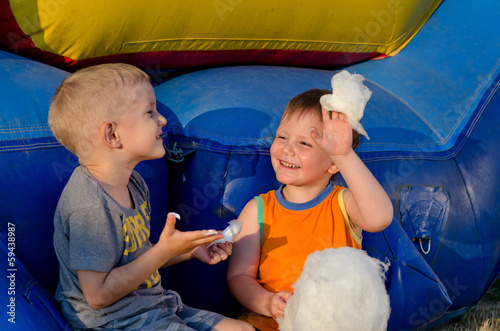 Photo: Two boys laughing as they share cotton candy Two boys laughing as they share cotton candy