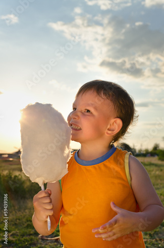 Photo: Young boy eating a stick of cotton candy Young boy eating a stick of cotton candy