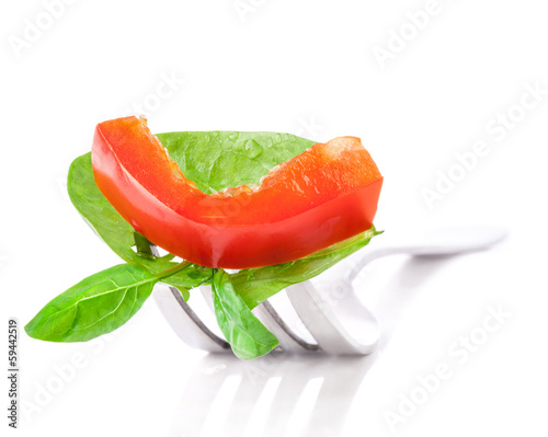 Photo: Bell pepper slice and leaf of basil on fork isolated on white ba Bell pepper slice and leaf of basil on fork isolated on white ba