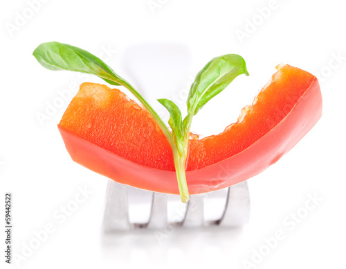Photo: Bell pepper slice and leaf of basil on fork isolated on white ba Bell pepper slice and leaf of basil on fork isolated on white ba