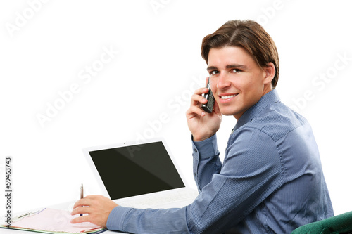 Photo: Happy business man on cell phone in front of laptop Happy business man on cell phone in front of laptop