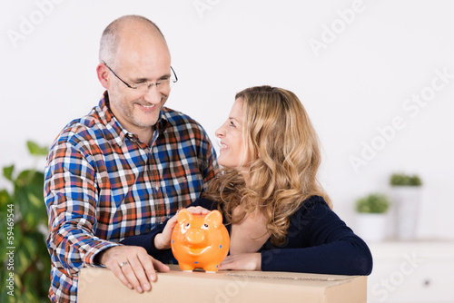 Photo: zufriedenes paar mit sparschwein und umzugskarton zufriedenes paar mit sparschwein und umzugskarton