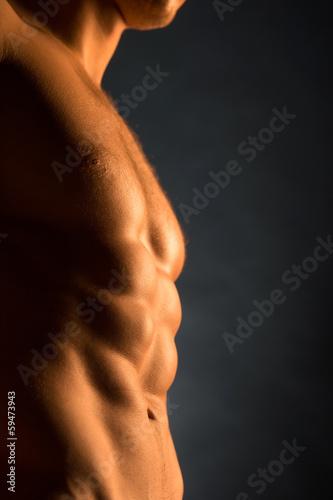 Photo: Close up of beautiful muscular male body in golden light Close up of beautiful muscular male body in golden light