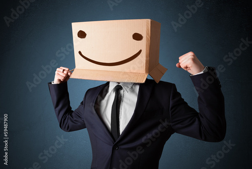 Photo: Businessman gesturing with a cardboard box on his head with smil Businessman gesturing with a cardboard box on his head with smil