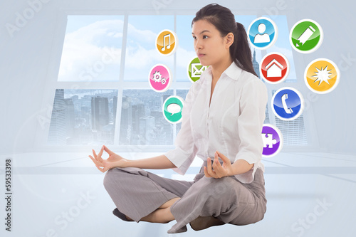 Photo: Composite image of businesswoman sitting in lotus pose Composite image of businesswoman sitting in lotus pose