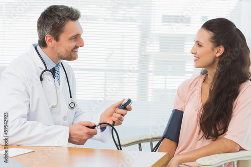 Photo: Male doctor checking blood pressure of a young woman Male doctor checking blood pressure of a young woman