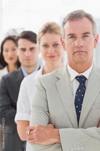 Photo: Business team standing in a line looking at camera Business team standing in a line looking at camera