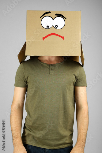 Photo: Man with cardboard box on his head on grey background Man with cardboard box on his head on grey background