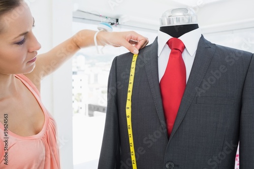 Photo: Female fashion designer measuring suit on dummy Female fashion designer measuring suit on dummy
