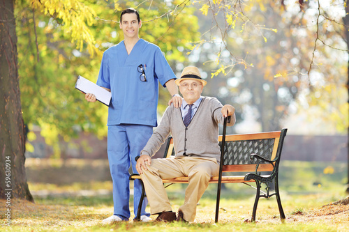 Photo: Healthcare professional standing next to a senior man in a park Healthcare professional standing next to a senior man in a park