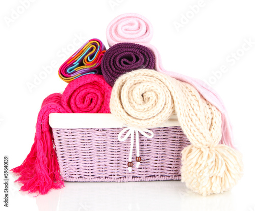Photo: Warm knitted scarves in basket isolated on white Warm knitted scarves in basket isolated on white