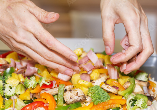 Photo: Hands arranging fresh vegetables and meat for pan pizza. Hands arranging fresh vegetables and meat for pan pizza.