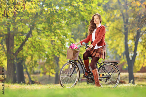 Photo: Young female on a bicycle in a park Young female on a bicycle in a park