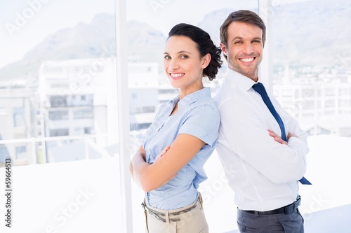 Photo: Smiling young business couple with arms crossed Smiling young business couple with arms crossed