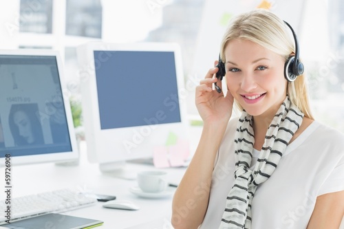 Photo: Smiling casual young woman with headset in office Smiling casual young woman with headset in office