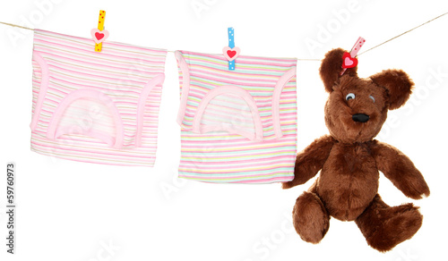 Photo: Baby clothes hanging on clothesline, isolated on white Baby clothes hanging on clothesline, isolated on white