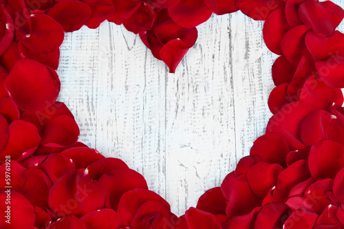 Photo: Beautiful heart of red rose petals on wooden table close-up Beautiful heart of red rose petals on wooden table close-up