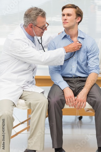 Photo: Doctor listening to his patients chest with stethoscope Doctor listening to his patients chest with stethoscope