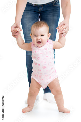 Photo: little baby girl doing first steps with help of mother little baby girl doing first steps with help of mother
