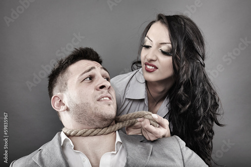 Photo: Man being tied by his neck with a rope by a woman Man being tied by his neck with a rope by a woman