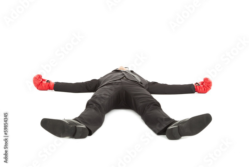 Photo: businessman was punched with boxing gloves and lie down on the f businessman was punched with boxing gloves and lie down on the f