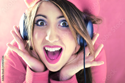 Photo: Happy shocked woman in pink listening to good music Happy shocked woman in pink listening to good music