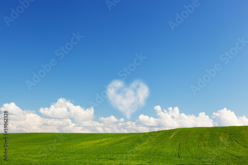 Photo: Heart shaped cloud above green summer field landscape Heart shaped cloud above green summer field landscape