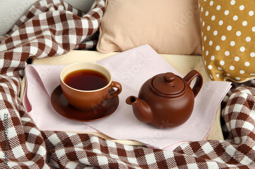 Photo: Cup and teapot on tray on bed close up Cup and teapot on tray on bed close up