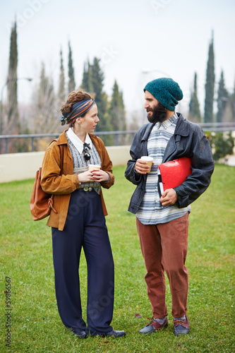 Photo: Hipster couple talking and drinking coffee to go Hipster couple talking and drinking coffee to go