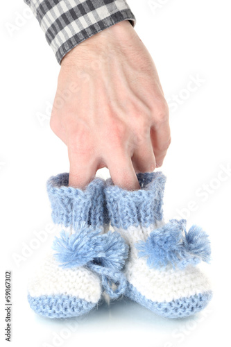 Photo: Hand with crocheted booties for baby, isolated on white Hand with crocheted booties for baby, isolated on white