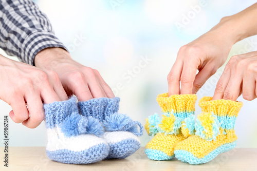 Photo: Hands with crocheted booties for baby, on light background Hands with crocheted booties for baby, on light background