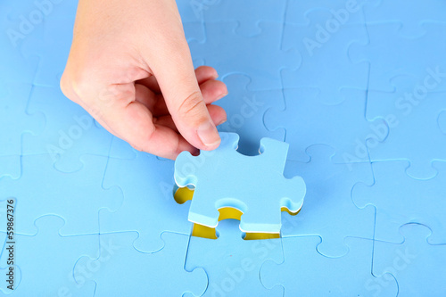 Photo: Hand holding puzzle piece, close up Hand holding puzzle piece, close up
