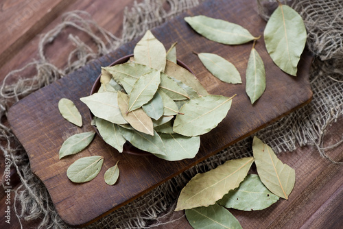 Photo: Dried bay leaves on a rustic cutting board, high angle view Dried bay leaves on a rustic cutting board, high angle view
