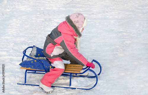 Photo: Little girl in pink playing on a toboggan Little girl in pink playing on a toboggan
