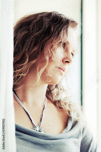 Photo: Sad beautiful woman looking out window Sad beautiful woman looking out window