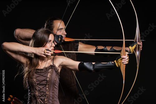 Photo: Young couple with bows and historical costumes Young couple with bows and historical costumes