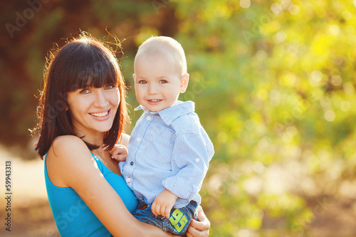 Photo: Portrait of beautiful happy smiling mother with baby outdoor Portrait of beautiful happy smiling mother with baby outdoor